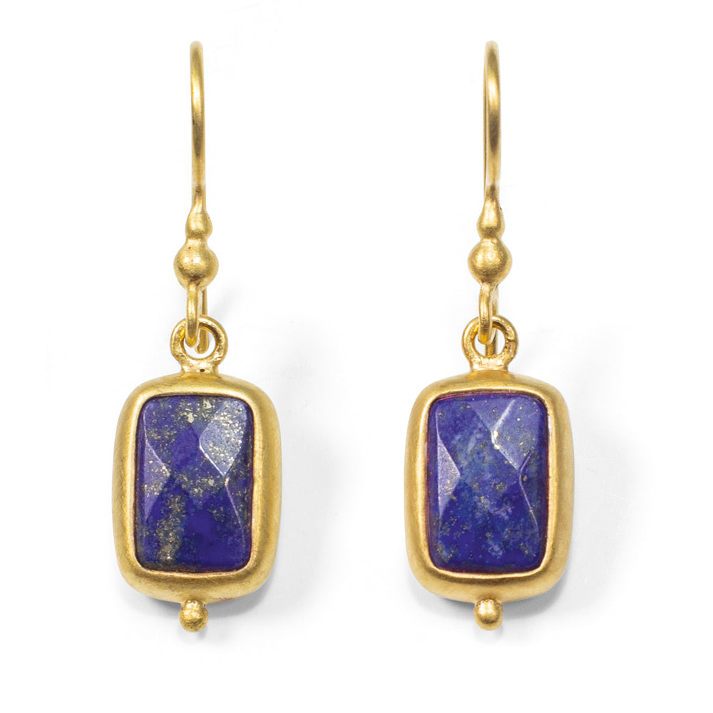 Die Ohrhänger „Falling Star“ sind goldene Tropfenohrringe mit rechteckigen blauen Steinen in goldenen Rahmen, die jeweils an einem einfachen goldenen Haken hängen.