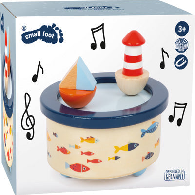 Die Spieluhr Großer Ozean ist eine Spieluhr mit einem Boot und einem Leuchtturm auf der Oberseite, verziert mit bunten Fischen und umgeben von Musiknoten.