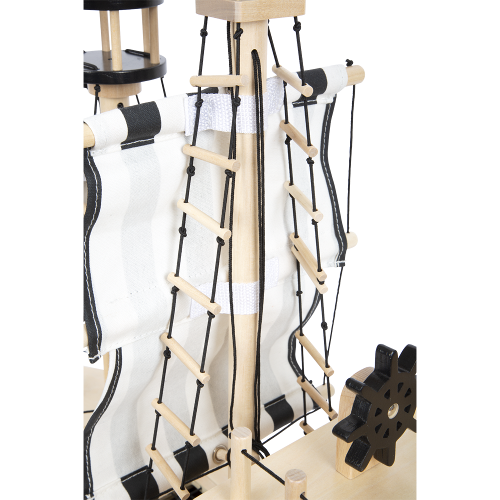 Nahaufnahme des Holzmastes des Piratenschiff-Spielzeugs mit schwarz-weißen Segeln, detaillierter Takelage und einem zahnradähnlichen Akzent.