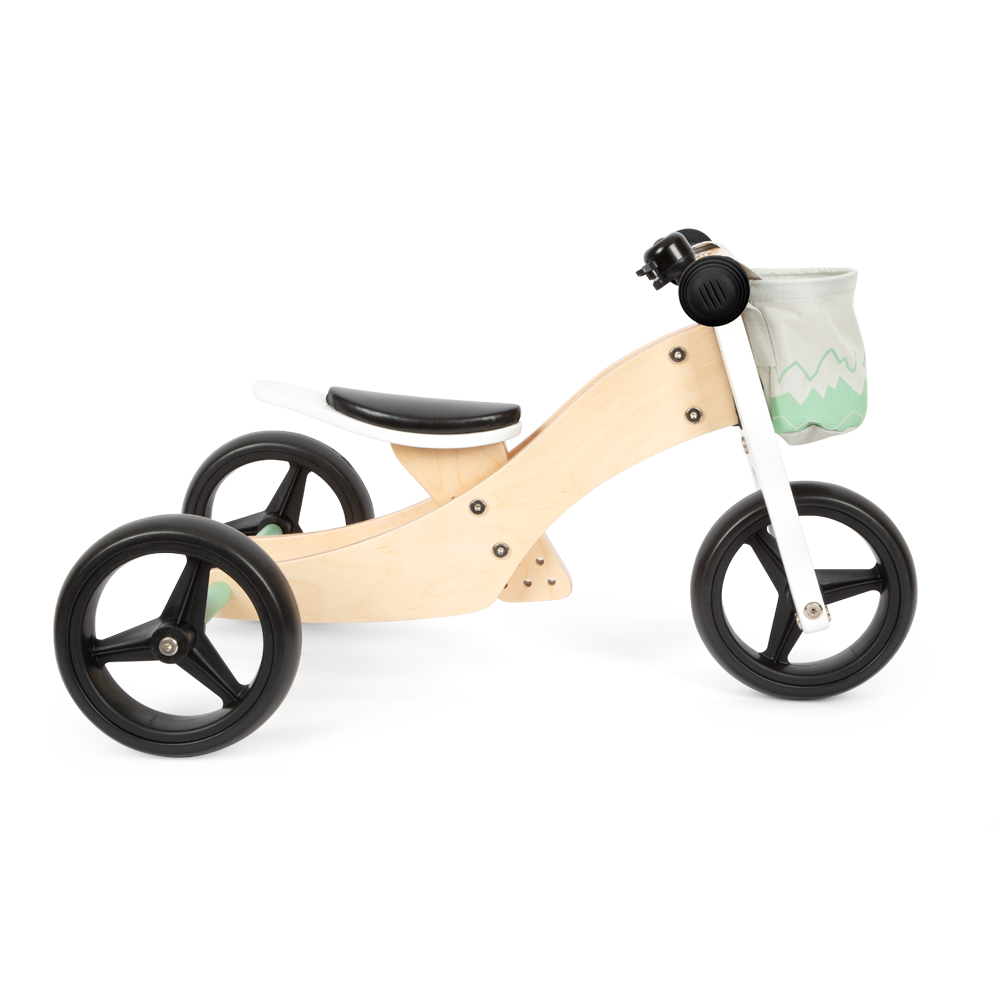Das Lauf- und Dreirad Salbeigrün ist ein hölzernes Balance-Dreirad mit schwarzen Rädern, einem schwarzen Sitz und einer kleinen mintgrünen Tasche, die am Lenker befestigt ist.