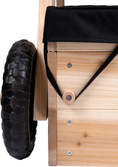 Die Nahaufnahme des Sandkastens mit Sitzgruppe und Matschtisch zeigt den Holzrahmen, das schwarze Rad und den schwarzen Stoff, der mit einem Riemen und einem Holzknopf befestigt ist.