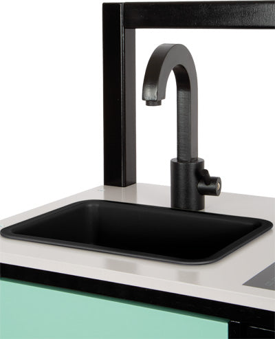 Die Kinderküche Industrial verfügt über einen schwarzen Wasserhahn, ein schwarzes Waschbecken und eine weiße Arbeitsplatte mit einem mintfarbenen Schrank darunter.