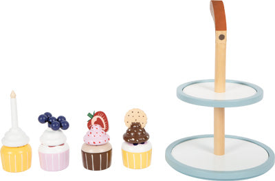 Die Cupcake Etagere „tasty“ besteht aus hölzernem Spielzeug-Cupcake mit Topping, der neben einem zweistöckigen Dessertständer aus Holz mit Griff platziert ist.