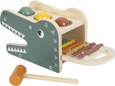 Das Klopfspiel mit Xylophon „Safari“ ist ein hölzernes Krokodilspielzeug mit Xylophontasten, bunten Bällen oben drauf und wird mit einem kleinen Holzschlägel geliefert.