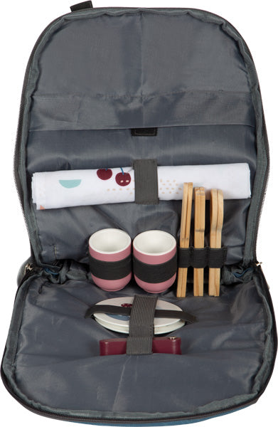 Der Picknickrucksack „tasty“ öffnet sich und gibt den Blick frei auf ordentlich angeordnete Teller, Tassen, Besteck und eine gerollte Serviette in separaten Fächern.