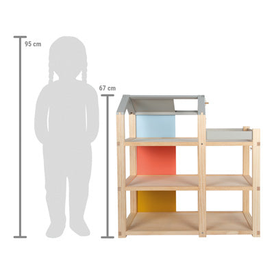 Das Puppenhaus Natur mit Möbeln verfügt über bunte Paneele und ist 67 cm groß. Neben ihm ist eine Kindersilhouette mit einer Größe von 95 cm abgebildet.