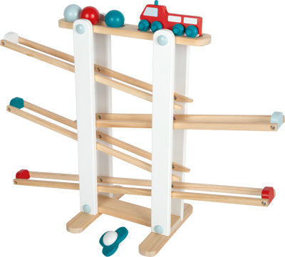 Die Kugelbahn ist eine hölzerne Spielzeugrampe mit roten und blauen Kugeln und einer roten Spielzeugeisenbahn, die obenauf bereit zum Losfahren steht.