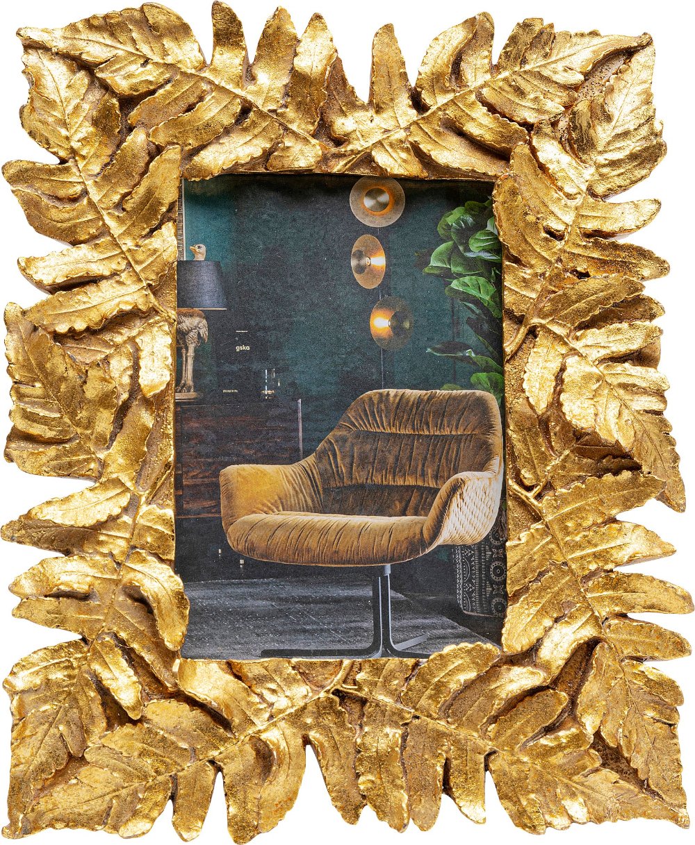 Der „Bilderrahmen Gold Leaves 10x15cm“ aus polyresinbeschichtetem, handgefertigtem Gold umrahmt ein Bild eines senfgelben Samtsessels in einem modernen, stilvollen Wohnzimmer mit Wandkunst und Lampe.