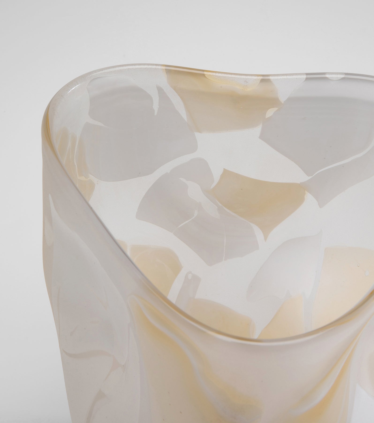 Eine Nahaufnahme der Vase Galicia Beige – ein durchscheinendes, skulpturales Stück mit weichen weißen und beigen Flecken und fließenden Konturen – setzt einen eleganten dekorativen Akzent vor einem schlichten weißen Hintergrund.