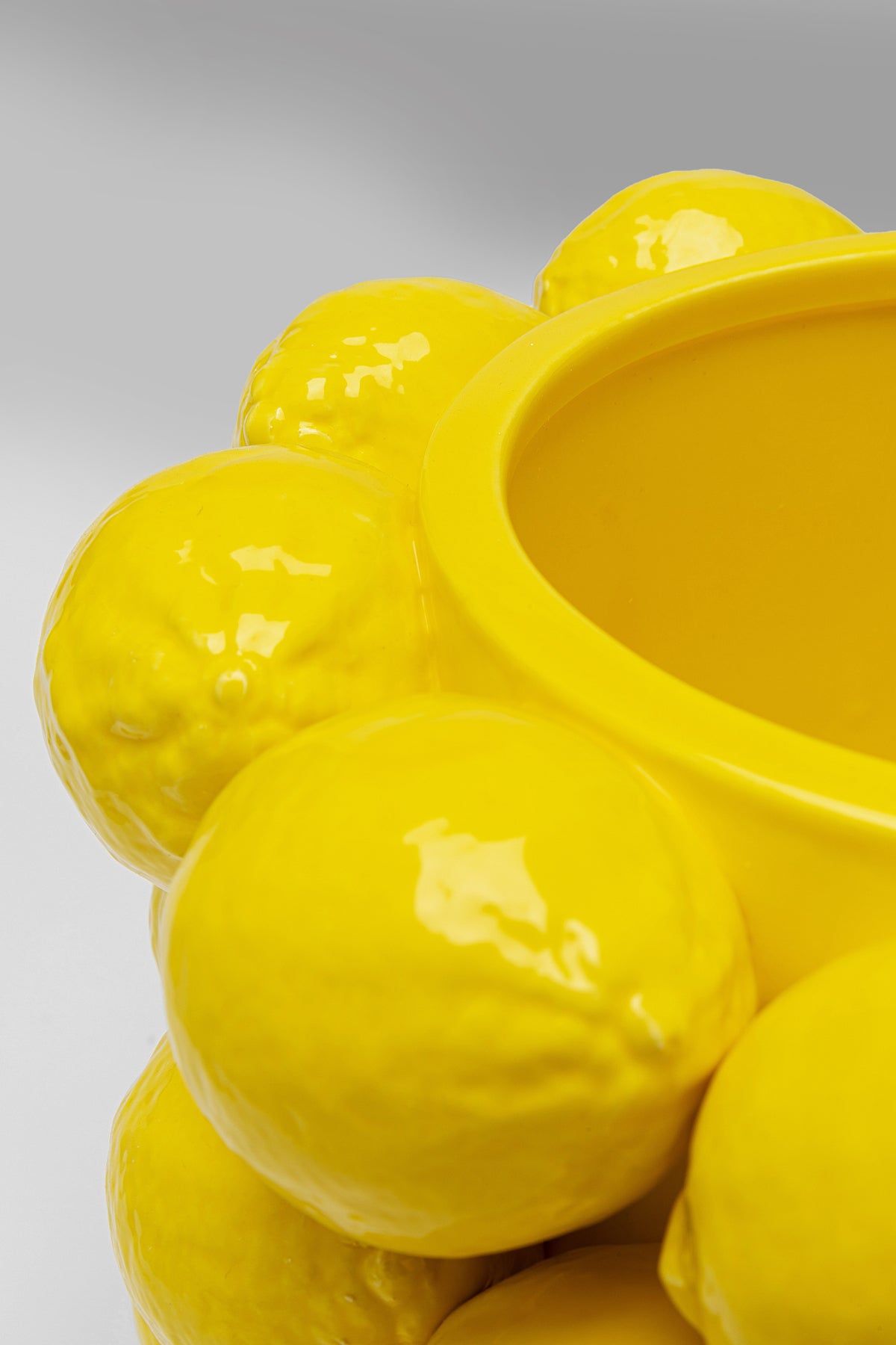 Nahaufnahme der Vase „Lemon Juice“ (19 cm), ein leuchtend gelbes Porzellanstück mit glänzenden, geformten Zitronenformen am Rand, vor einem neutralen grauen Hintergrund.
