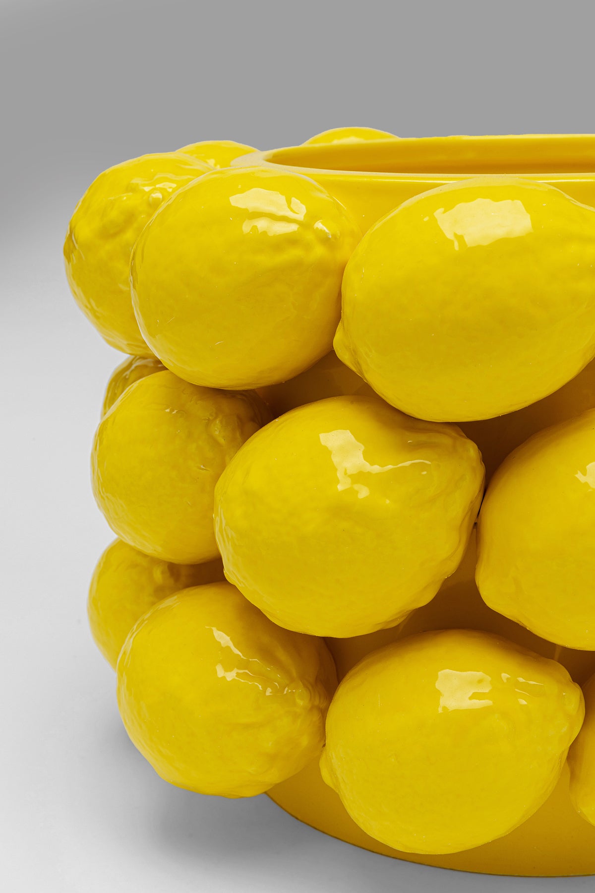 Eine Nahaufnahme der 19 cm großen Vase „Lemon Juice“ mit einem leuchtend gelben Design und glänzenden, dreidimensionalen Zitronen, die die glasierte Porzellanoberfläche vor einem schlichten grauen Hintergrund zieren.