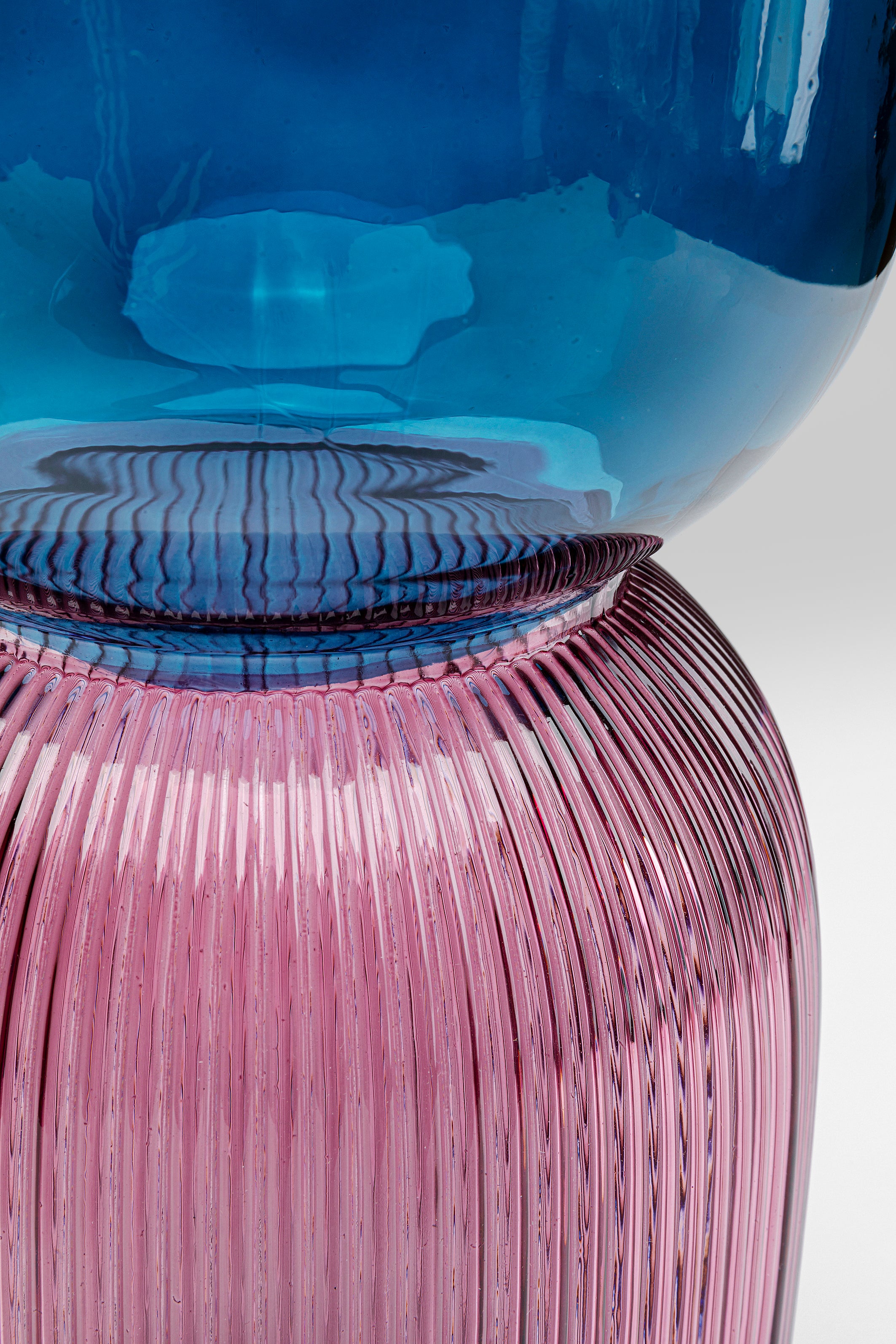 Nahaufnahme der Vase Marvelous Duo Blau Lila mit einem glatten, abgerundeten blauen Oberteil und einem gerippten rosa Unterteil. Das Bild hebt die kontrastierenden Farben und die komplexen Details dieser einzigartigen Glasvase hervor.