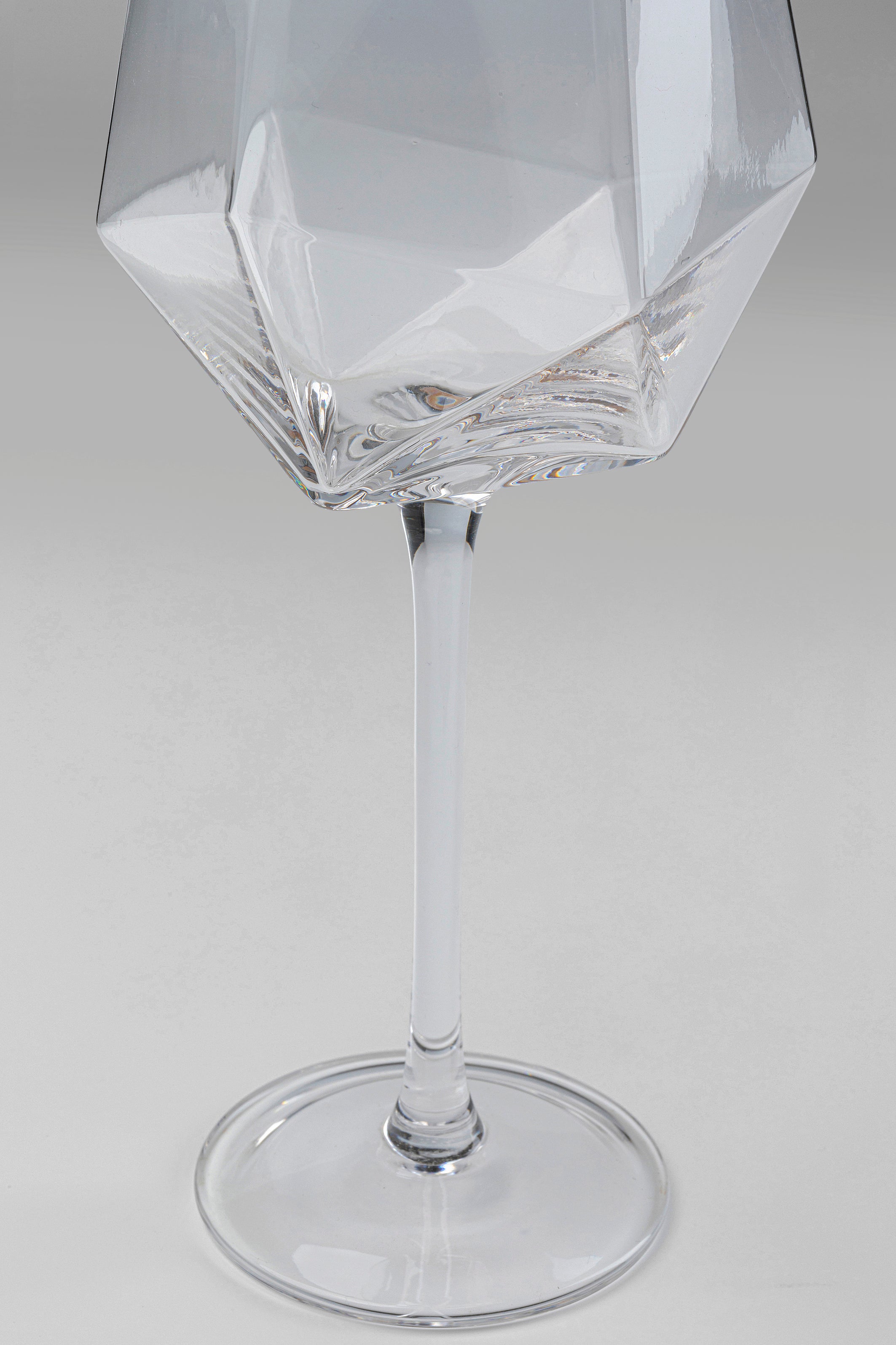 Eine Nahaufnahme des Weinglases Diamond Gold Rim (4/tlg.) zeigt seine geometrisch facettierte Schale, den schlanken Stiel, den runden Fuß und den eleganten Goldrand vor einem hellgrauen Hintergrund.
