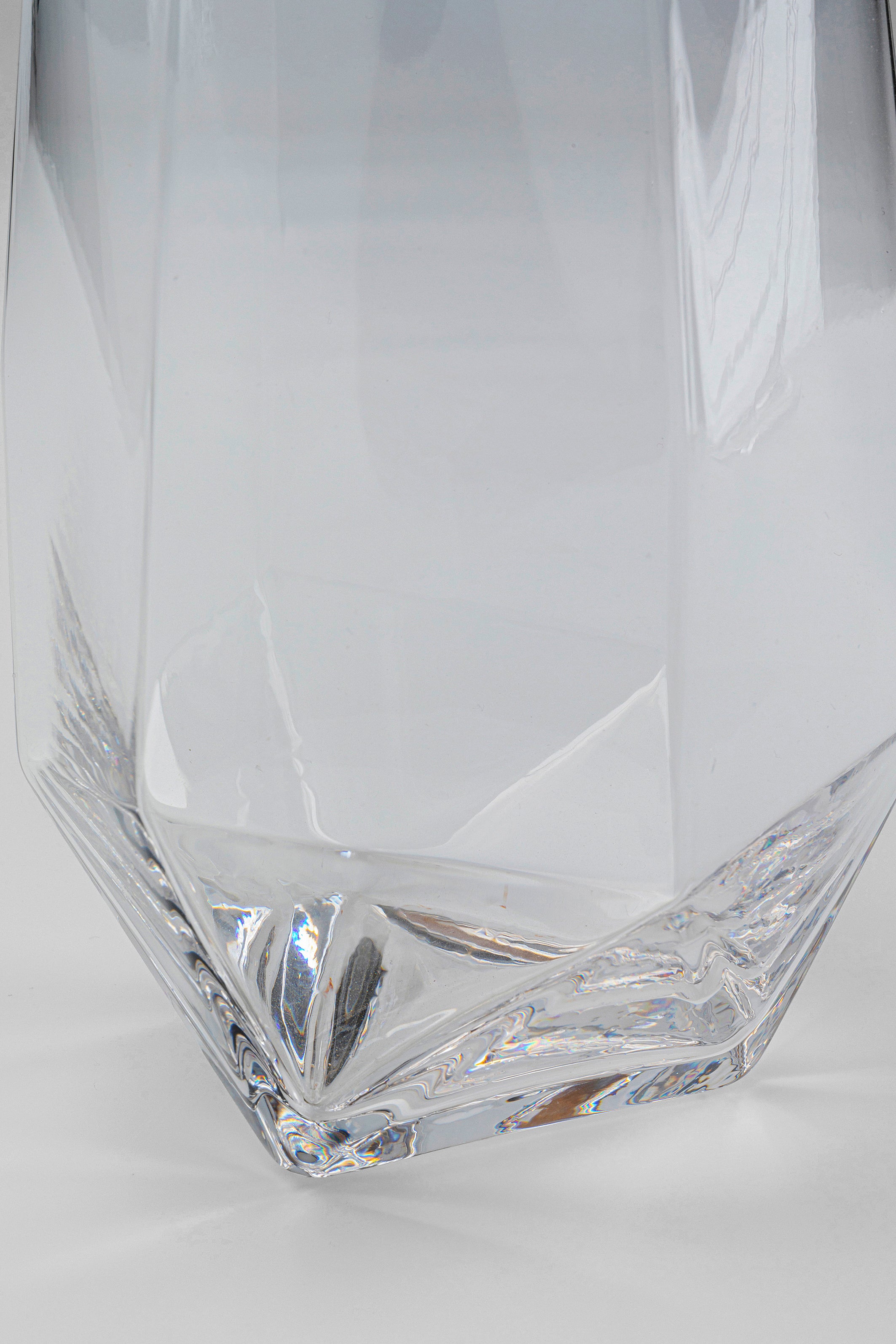Nahaufnahme des facettierten Bodens eines Wasserglases Diamond Gold Rim (4/tlg.), dessen geometrische, reflektierende Oberflächen vor einem weißen Hintergrund glänzen – perfekt, um jedes Tischgedeck aufzuwerten.