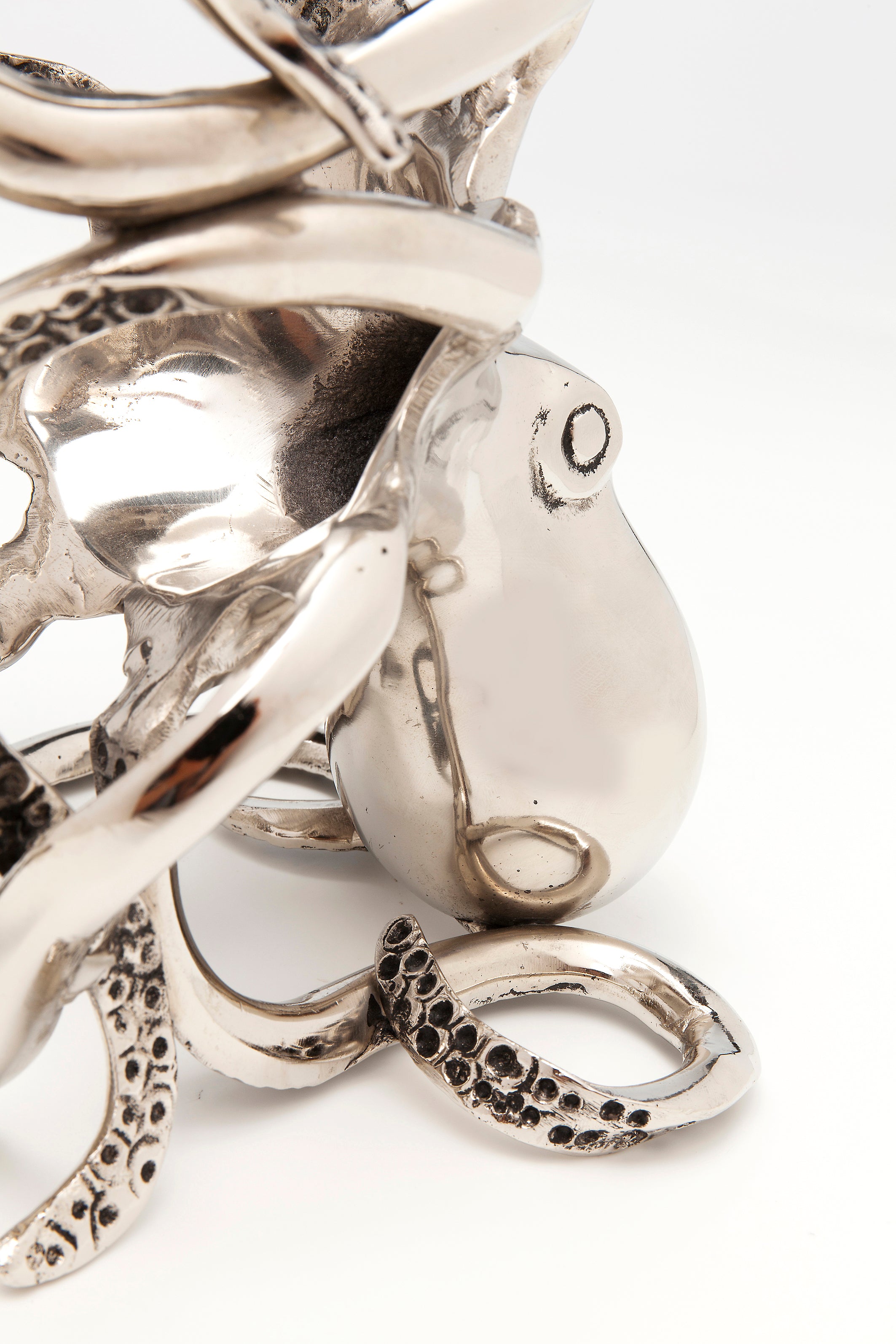Eine Nahaufnahme der glänzenden, metallischen Flaschenhalter-Oktopus-Skulptur hebt ihre detaillierten Tentakeln und strukturierten Saugnäpfe hervor – dekorativ gestaltet und perfekt als Geschenk – vor einem schlichten weißen Hintergrund.