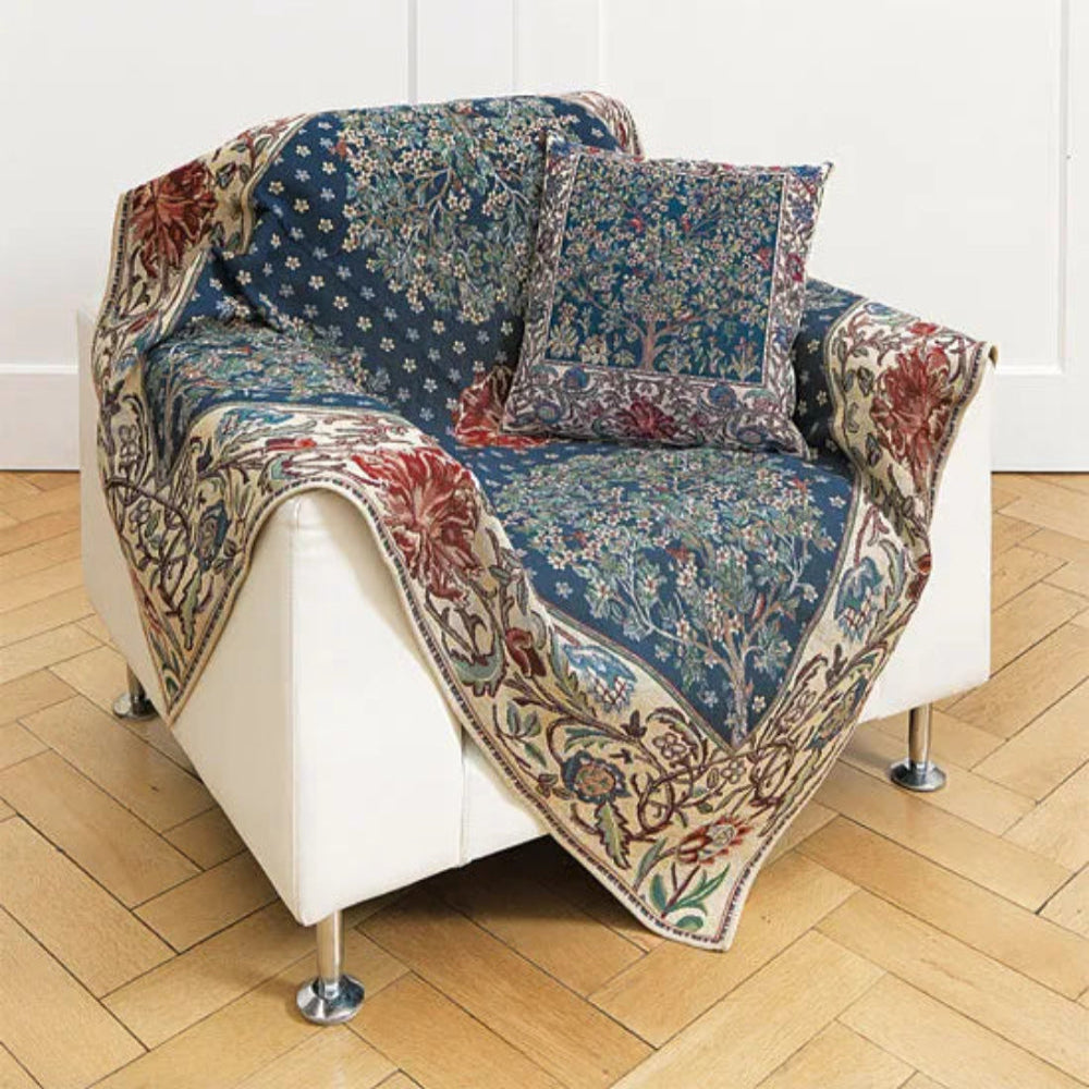 Ein weißer Sessel, bezogen mit einer gemusterten blau-beigen Decke und einem passenden Zierkissen.