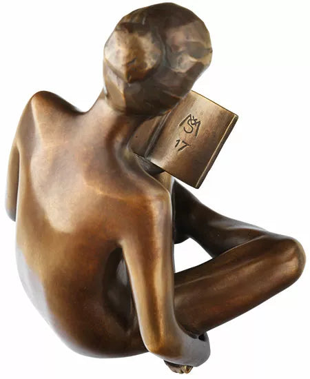 Bronzeskulptur einer sitzenden, nackten Figur, die ein Buch liest, von hinten und leicht von oben betrachtet.