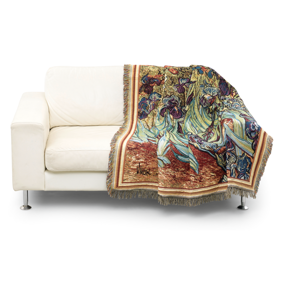 Weißes Sofa mit dem Vincent van Gogh Wohnplaid „Iris (Schwertlilien)“, einer farbenfrohen Fransendecke mit Iris-Muster, die über einer Armlehne hängt.