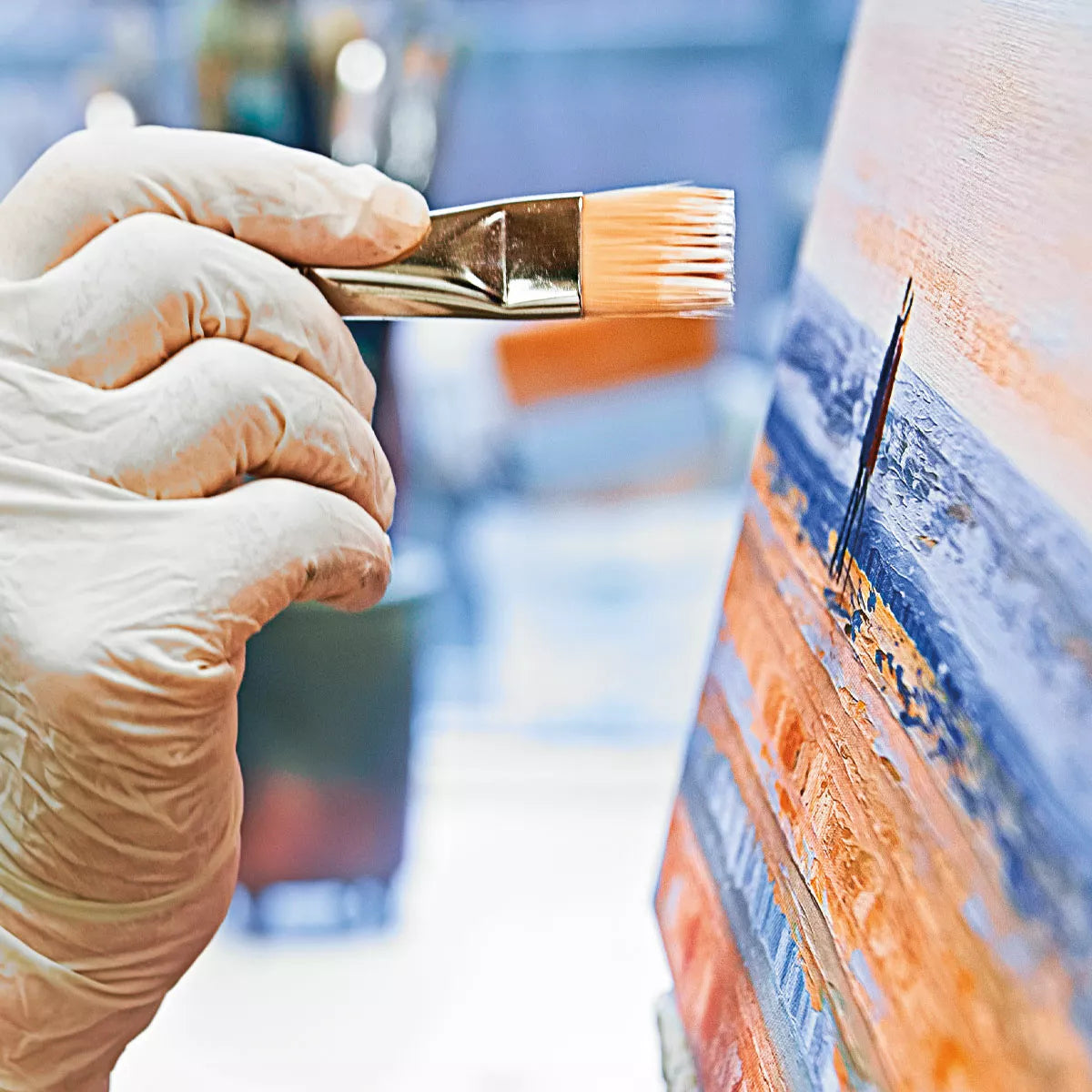 Eine behandschuhte Hand malt bunte abstrakte Muster auf das gerahmte Kunstwerk „Leises Meeresrauschen – Jubiläums-Edition“ (2022, serielles Unikat) von Anja Struck.