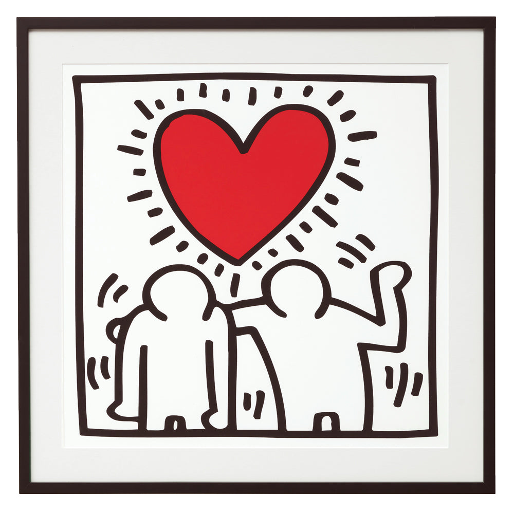 In Keith Harings gerahmtem Druck „Untitled (Be Mine)“ (1987), der in seinem ikonischen, schlichten Grafikstil gestaltet ist, stehen zwei Figurenumrisse zusammen unter einem großen roten Herz mit strahlenförmigen Linien.