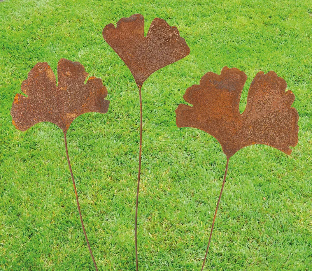 Drei Gartenstecker „Ginkgoblatt“-Metallblattskulpturen stehen auf einer grünen Rasenfläche.
