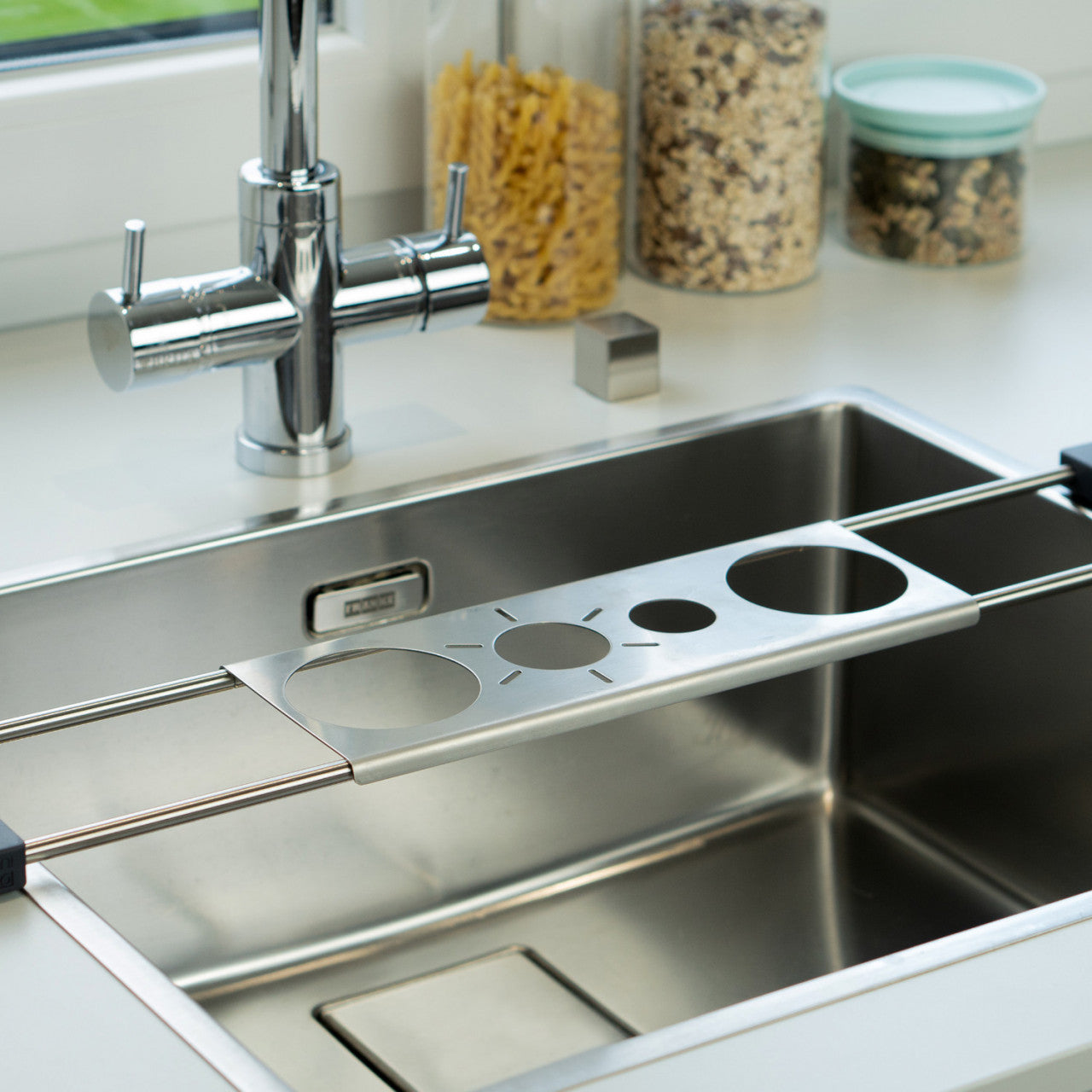 Abtropfhilfe Drip.it verstellbares Nudelsieb aus Metall mit vier Messlöchern, konzipiert für die Verwendung über einer modernen Küchenspüle.