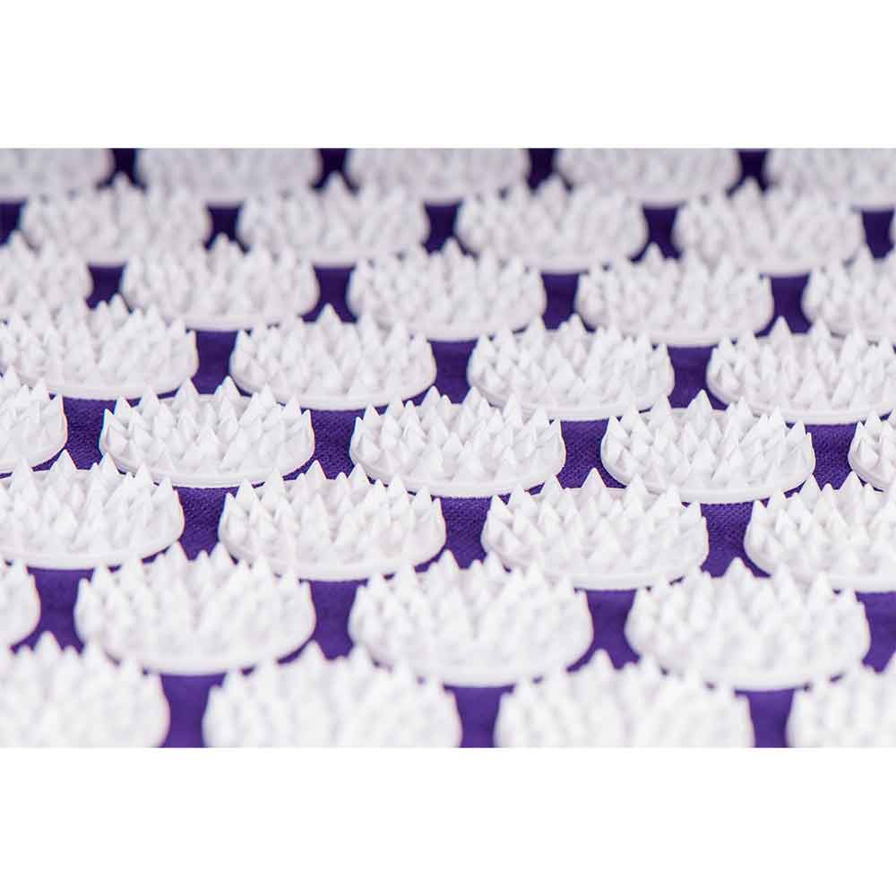 Nahaufnahme mehrerer weißer Plastikstacheln, die in kreisförmigen Mustern auf einer violetten Fläche angeordnet sind.