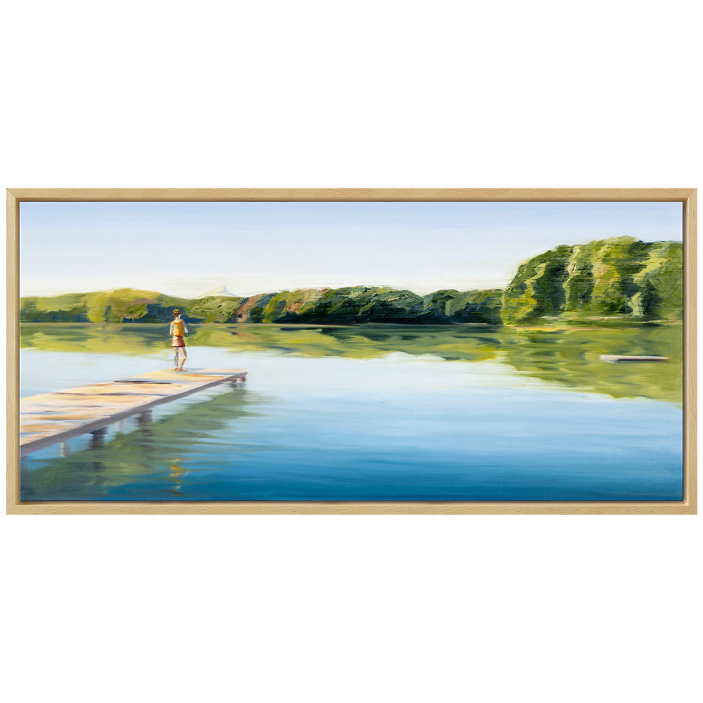 Eine Person steht auf einem Steg über ruhigem Seewasser, wie in Anja Strucks gerahmtem Kunstwerk „Die Natur malt Farben in meinem Herzen“ (2023), in der Ferne spiegeln sich Bäume und Himmel.