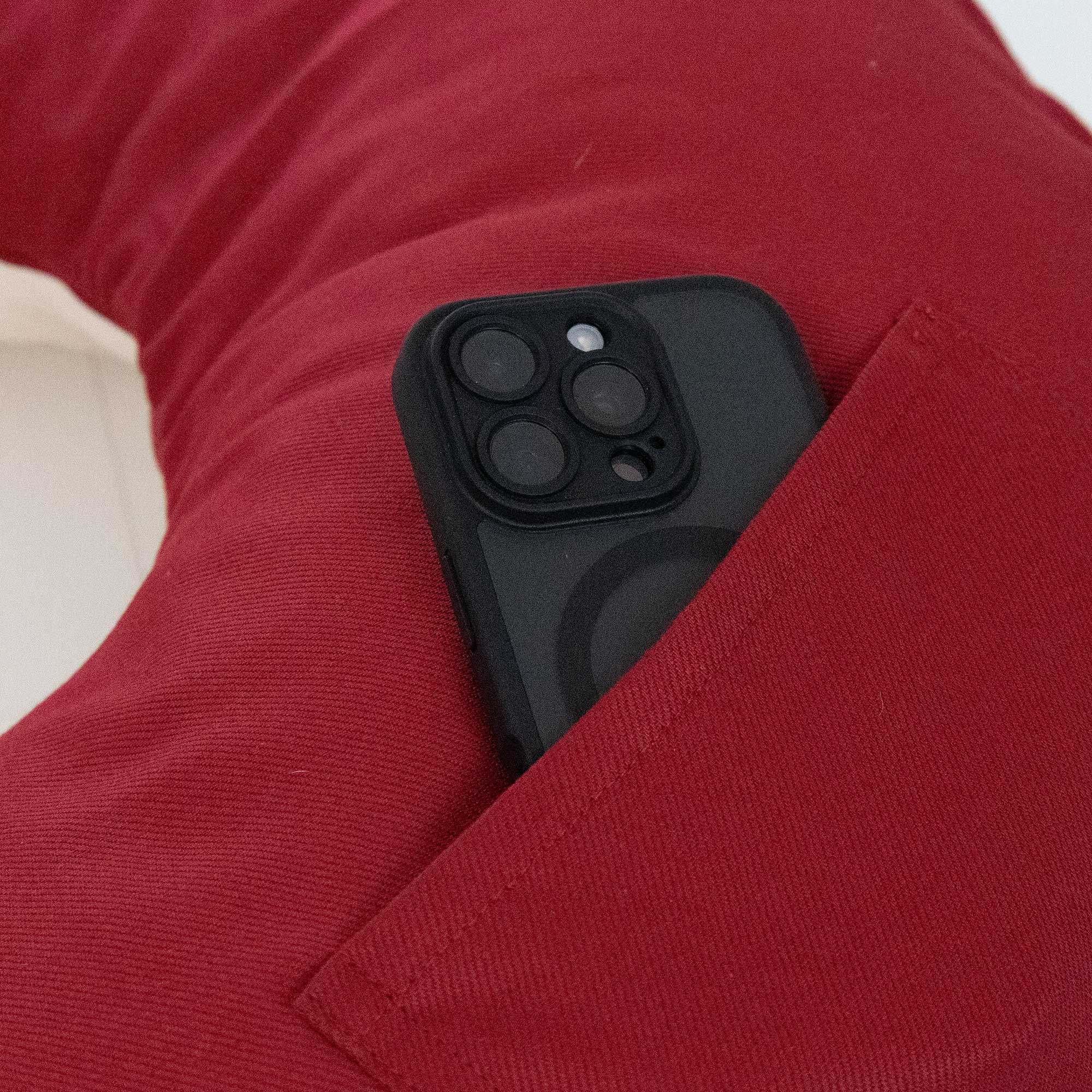 Ein schwarzes Smartphone in der Tasche eines roten Kissens.
