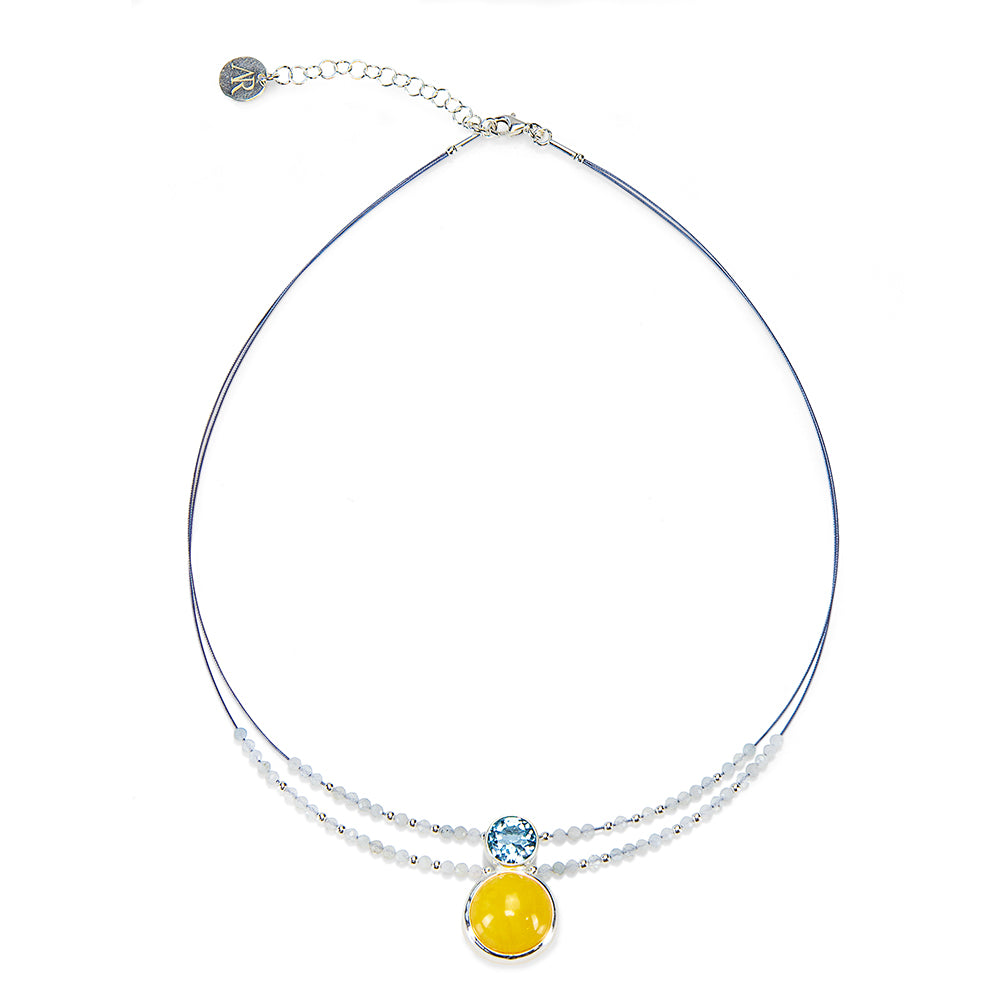 Das Bernsteincollier „Camille“ ist eine dünne Drahtkette mit kleinen weißen Perlen und zwei runden Anhängern, einem gelben und einem hellblauen.