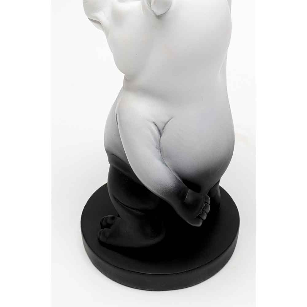 Eine schwarz-weiße Bärenfigur steht auf einem runden schwarzen Sockel, von der Seite gesehen.