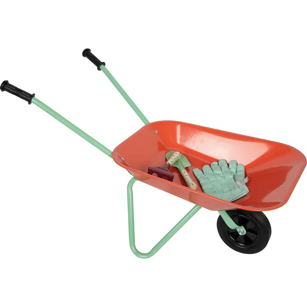 Eine rote Schubkarre mit grünen Griffen enthält Gartenhandschuhe, eine kleine Schaufel und eine Handharke.