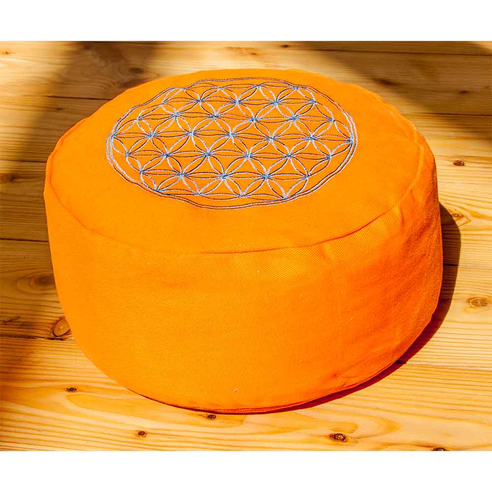Leuchtend orangefarbenes, rundes Kissen mit einem geometrischen Blumenmuster auf der Oberseite, platziert auf einem Holzboden.