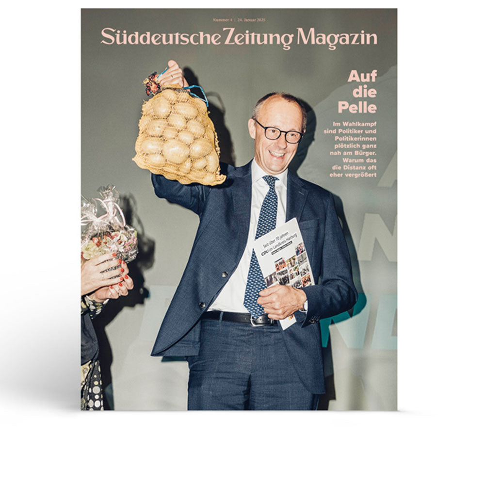 Ein lächelnder Mann im Anzug hält einen Netzbeutel mit Kartoffeln und eine Zeitschrift auf dem Cover des Süddeutsche Zeitung Magazins hoch.