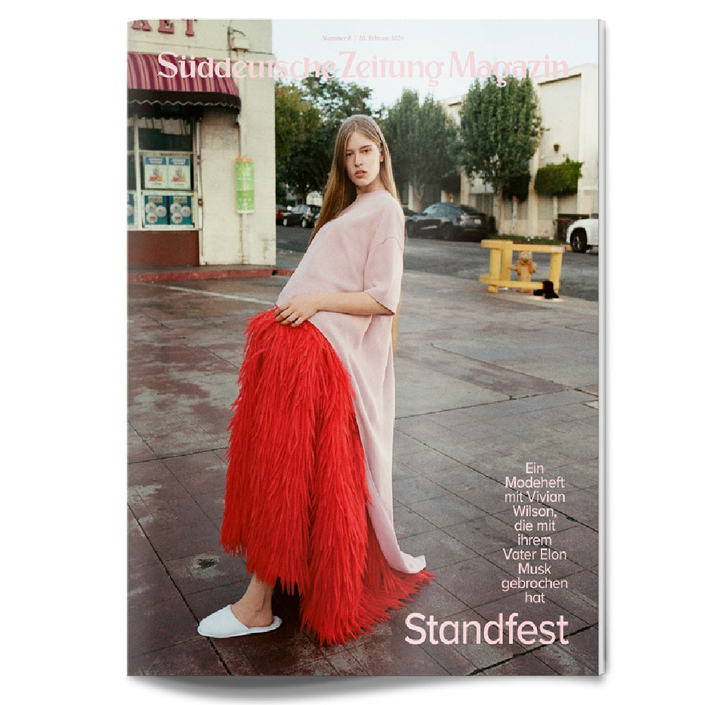 Eine Frau in einem langen, blassrosa Kleid mit leuchtend roten Fransen steht auf einem städtischen Bürgersteig. Der Umschlagtext lautet "Süddeutsche Zeitung Magazin" und enthält weitere Artikelüberschriften in deutscher Sprache.
