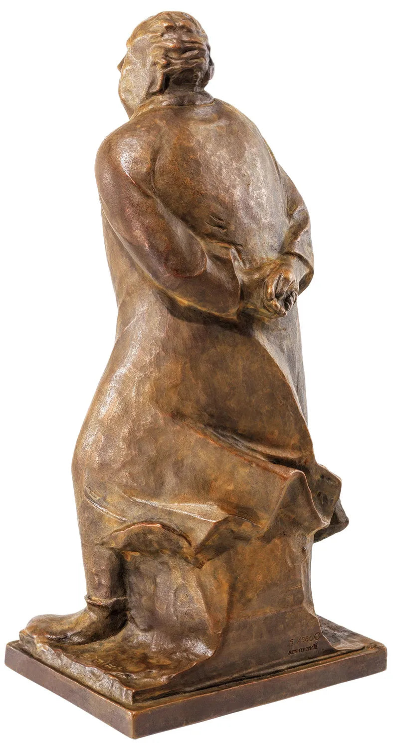 Bronzestatue einer Person in einem Mantel, die Hände hinter dem Rücken verschränkt, auf einem rechteckigen Sockel stehend.