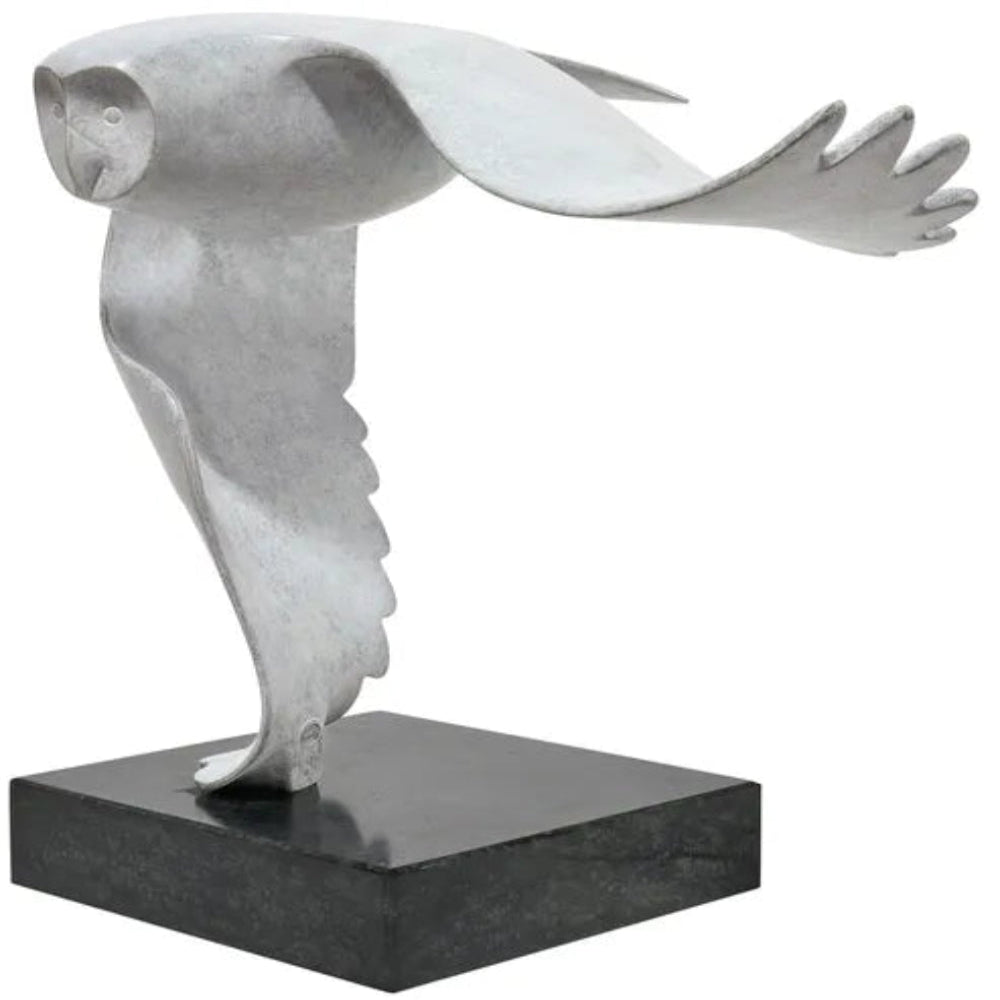 Skulptur einer stilisierten Eule im Flug, montiert auf einem schwarzen rechteckigen Sockel.
