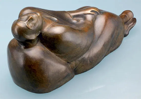 Bronzeskulptur einer liegenden, abstrakten menschlichen Figur mit weichen, abgerundeten Formen vor hellem Hintergrund.