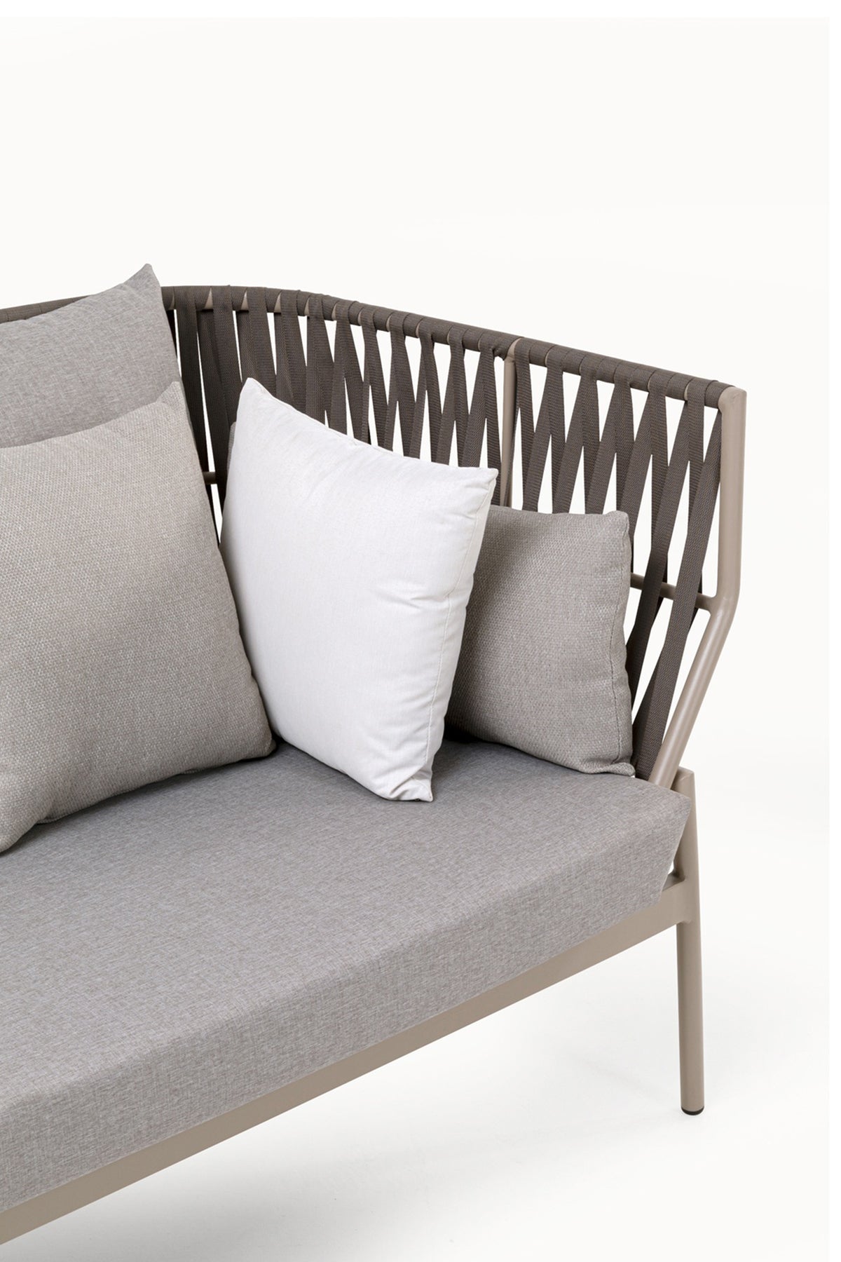 Modernes Outdoor-Sofa mit taupefarbenem Gestell, geflochtener Rückenlehne und drei Kissen - zwei graue und ein weißes - vor einem schlichten weißen Hintergrund.