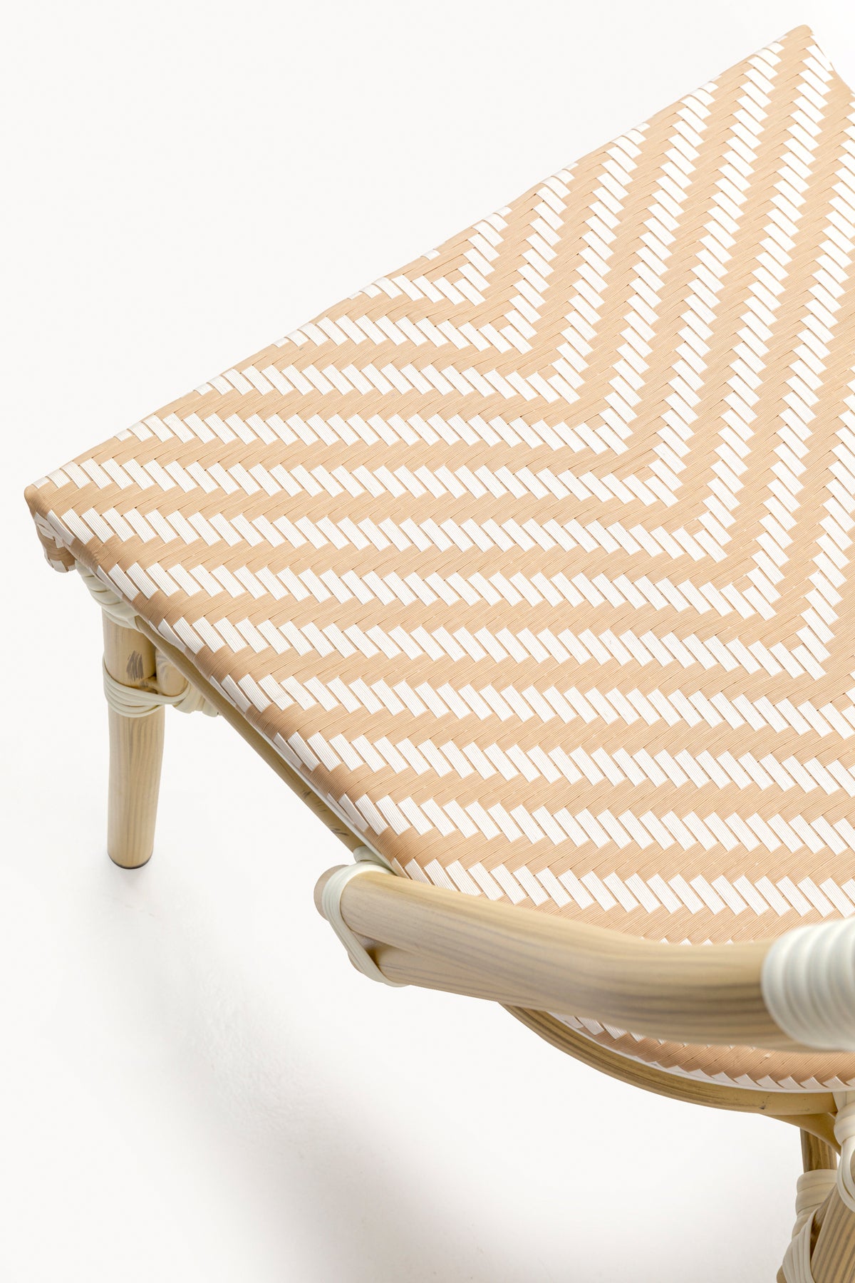 Nahaufnahme eines Stuhlsitzes mit beige-weißem Chevron-Webmuster, der einen Teil des gebogenen Holzrahmens und der Beine zeigt.