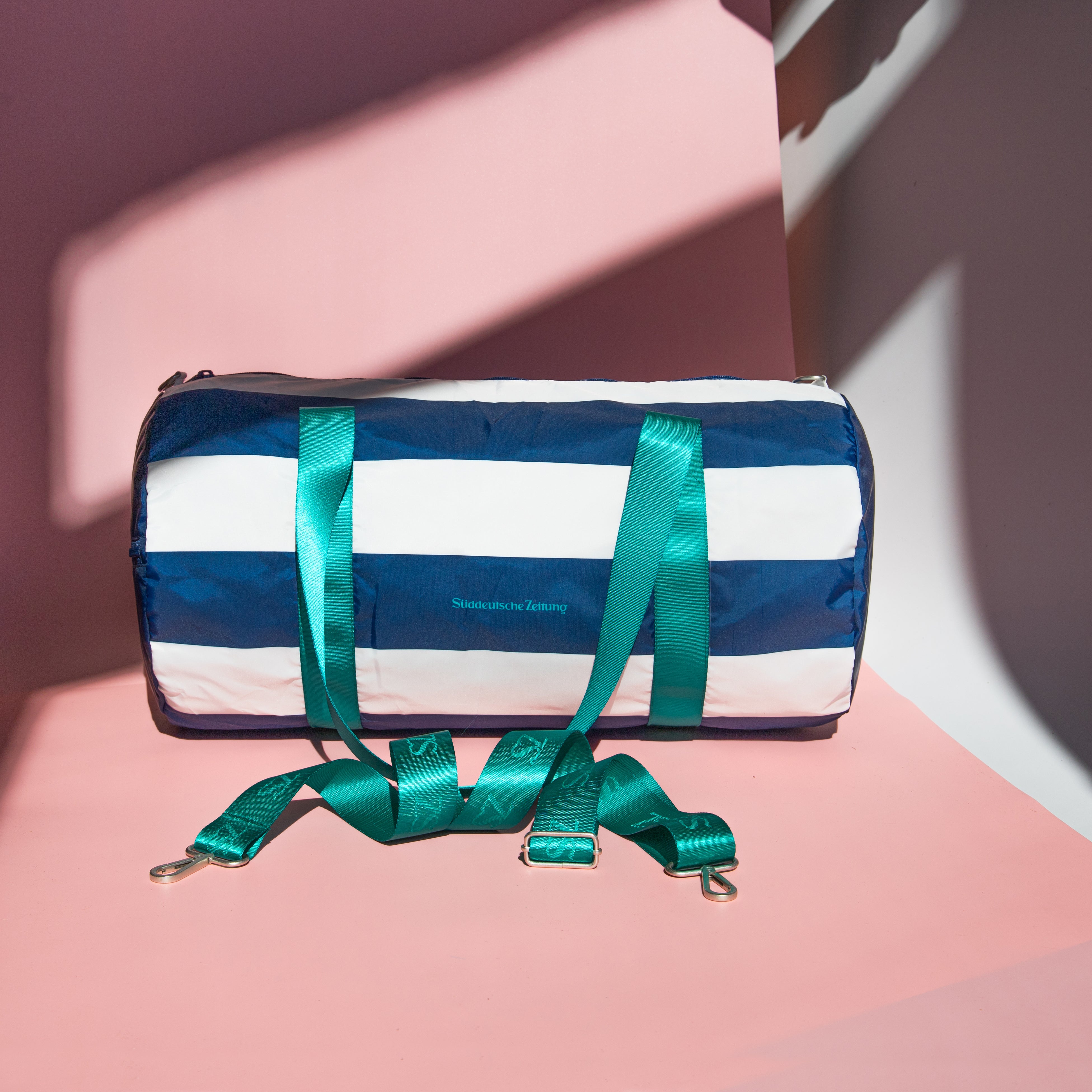 Tasche Weekender blau weiß gesreift mit grünen Henkeln und Logo Süddeutsche Zeitung auf rosa Hintergrund