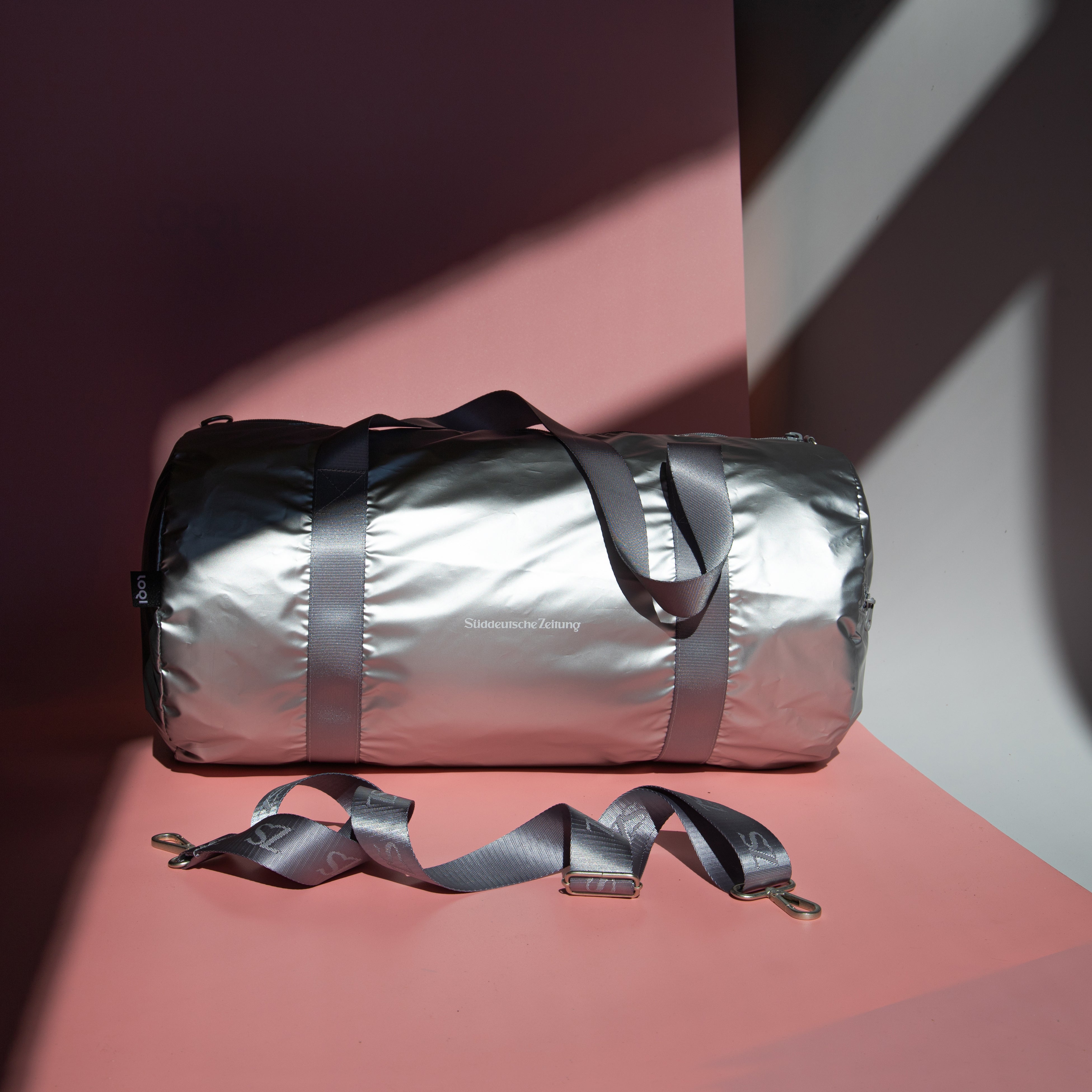 Tasche Weekender silber mit silbernen Henkel und Logo Süddeutsche Zeitung auf rosa Hintergrund