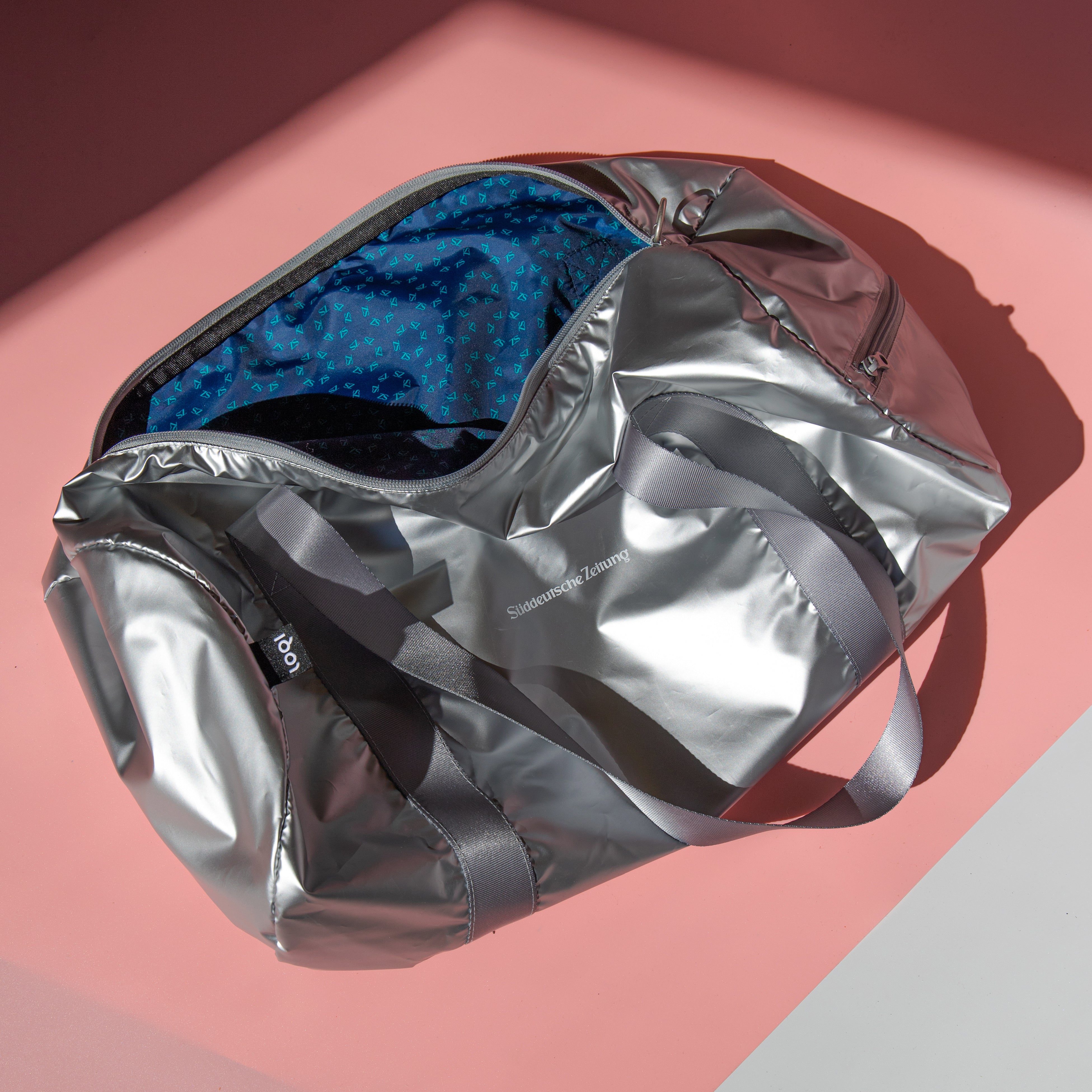 Tasche Weekender silber mit silbernen Henkel und Logo Süddeutsche Zeitung. Die Tasche ist für die Innenansicht halb geöffnet