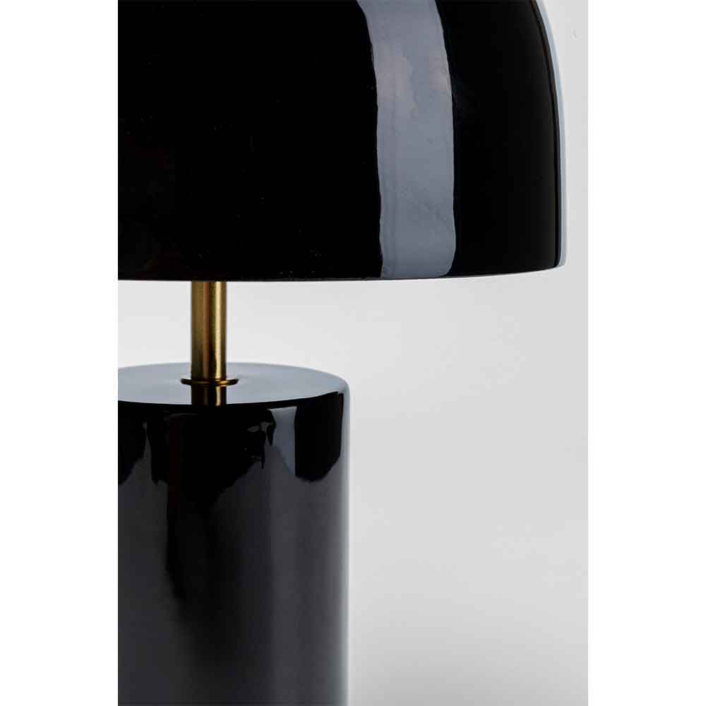 Nahaufnahme einer modernen schwarzen Tischlampe mit glänzender Oberfläche und Messingakzent auf hellem Hintergrund.