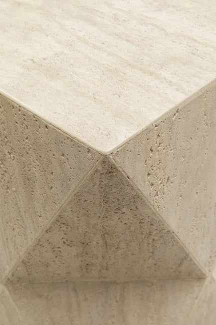Nahaufnahme einer beigen Stein- oder Marmortischecke mit einer glatten, polierten geometrischen Oberfläche.