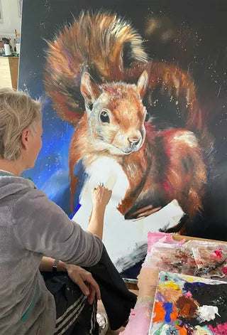 Eine Künstlerin stellt Sabrina Secks gerahmtes Kunstwerk „Hydra“ (2023) auf einer Leinwand aus, in der Nähe sind Malutensilien zu sehen.