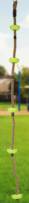 Das Kletterseil Himmelsstürmer, eine Strickleiter mit grünen Stufen, hängt im Freien über Gras, mit verschwommenen Bäumen und einem Spielplatz im Hintergrund.