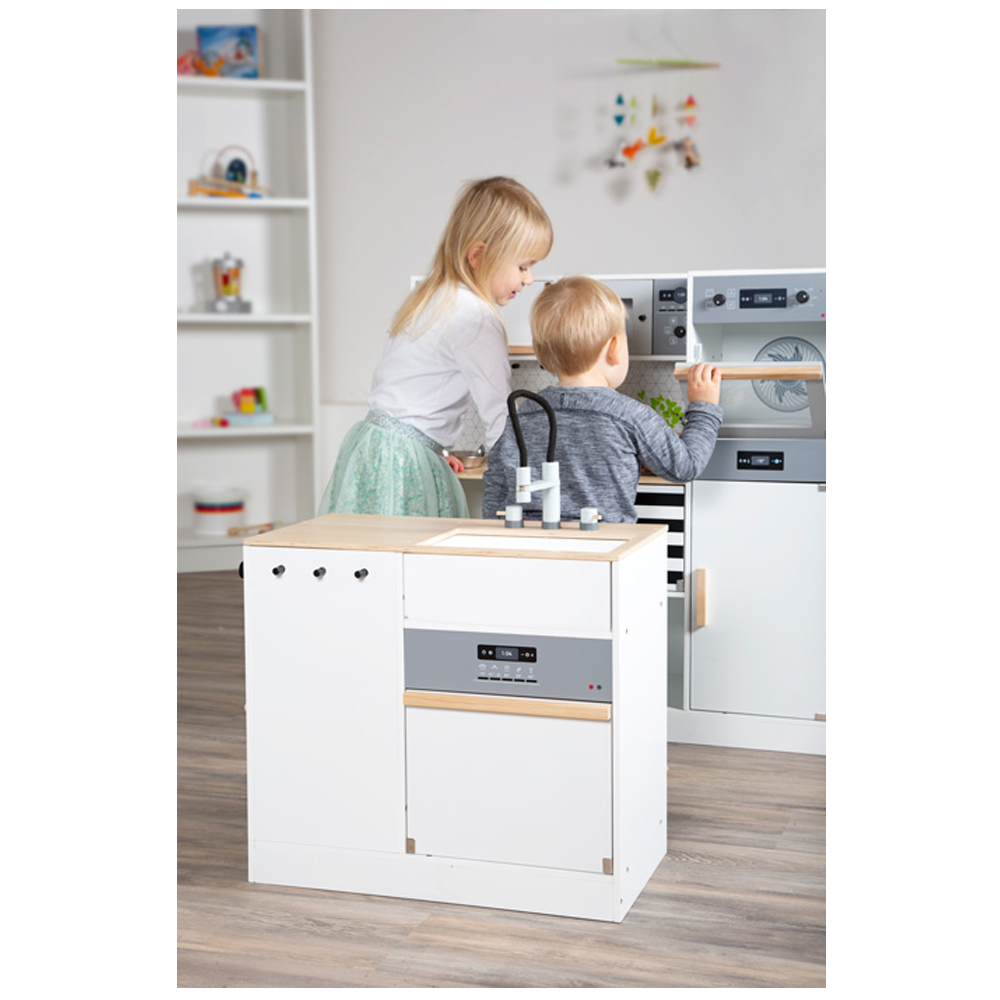 Zwei kleine Kinder spielen zusammen mit der Kinderküche modular XL, einem weißen Spielzeugküchenset, in einem hellen, modernen Raum.
