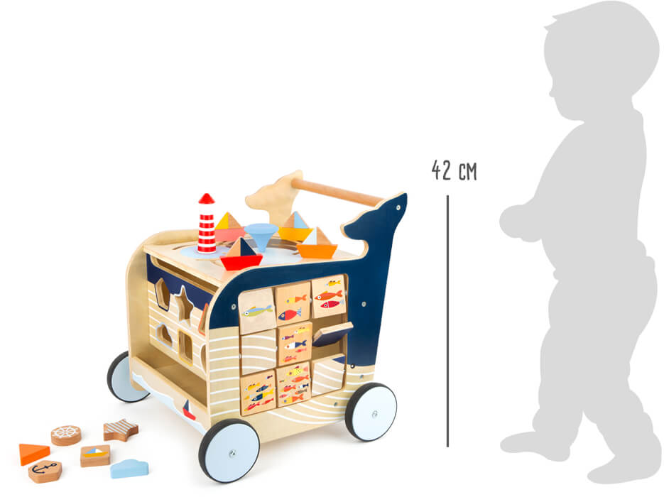 Lauflernwagen Wal mit Bauklötzen, neben einer Kindersilhouette abgebildet, um seine Größe von 42 cm anzuzeigen.