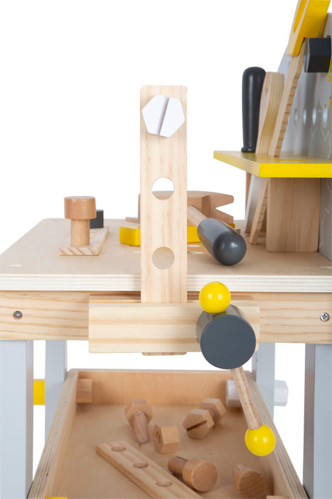 Die Werkbank kompakt „Miniwob“ ist eine Spielzeug-Werkbank aus Holz mit Werkzeug und Zubehör, darunter Hammer, Schraubenschlüssel und Schrauben in den Farben Natur und Gelb.